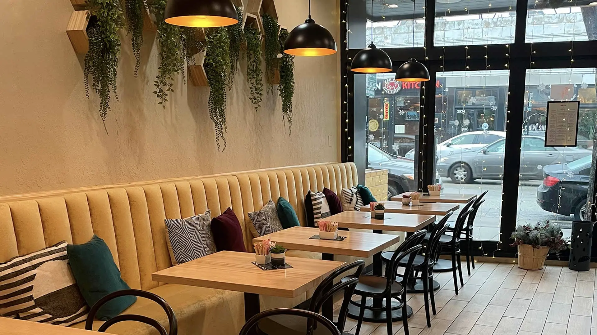 Korzo’s intimate dining room with yellow banquette seating and tables beside the Broadway windows
